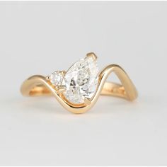 a yellow gold ring with two pear shaped diamonds on the band and an oval cut diamond in the center