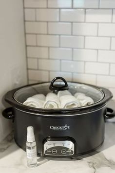 a slow cooker with rolls in it on a kitchen counter next to a bottle of deodorant