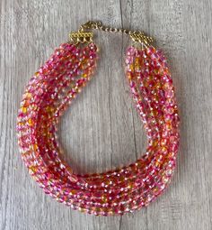 A gorgeous beaded statement necklace made with pink and orange faceted crystal beads. - 6 strands (more are listed)- Shortest strand measures 18.75 - 20.75" (will vary depending on clasp)- Gold stainless steel lobster claw (sterling silver, gold filled, stainless steel are also available) - 2" gold stainless steel extender chain- Lead free pewter multi strand connectorThe necklace length can also be customized. The mannequin's neck size is 14.5" for your reference. .A matching bracelet and earri Crystal Statement Necklace, Orange Crystals, Beaded Statement Necklace, Matching Bracelet, Multi Strand Necklace, Glass Bead Necklace, Faceted Crystal, Matching Bracelets, Pink Crystal