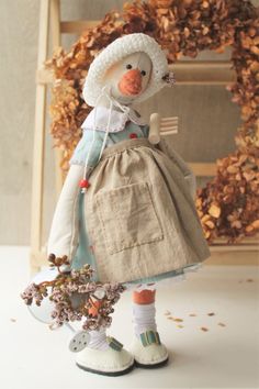 a doll is holding a flower in her hand and standing next to a wooden chair