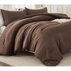 a bed covered in brown sheets and pillows