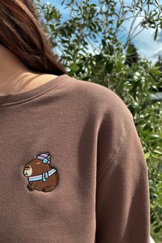 Add a touch of winter charm to your wardrobe with our Winter Capybara Embroidered Crewneck Sweatshirt. Made from a soft cotton blend, this relaxed fit pullover features an adorable capybara embroidery with a winter theme, capturing the essence of charming and unique style. The unisex design makes it perfect for everyone, offering a stylish and comfortable option for any casual occasion. Whether you're lounging at home or heading out, this sweatshirt brings warmth and seasonal flair to your look. Winter Long Sleeve Tops With Embroidered Patch, Embroidered Long Sleeve Winter Tops, Long Sleeve Tops With Embroidered Patch For Winter, Winter Embroidered Patch Crew Neck Sweatshirt, Winter Crew Neck Sweatshirt With Embroidered Patch, Capybara Embroidery, Lover Fashion, Embroidered Crewneck, Embroidered Sweatshirt