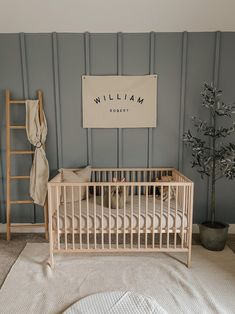 a baby's room with a crib, ladder and tree in the corner