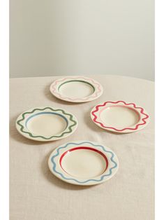 four plates with scalloped edges on a table