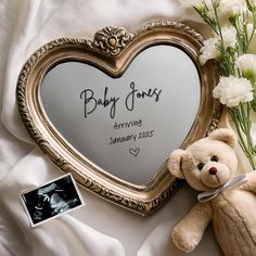 a teddy bear sitting next to a heart shaped mirror with the name baby jones written on it