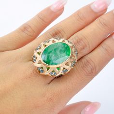 This exquisite cocktail ring features a stunning emerald as the centerpiece, radiating with its vivid green hue. The emerald is encased in an intricate lattice setting of rose gold, enhancing its natural allure. Surrounding the centerpiece are sparkling London Blue Topaz accent stones, adding a layer of depth and sophistication to the ring. The openwork design beneath the stone creates an ethereal play of light, allowing the emerald to glow from within. This ring is a statement of elegance, perf Art Deco Round Green Emerald Ring, Art Deco Green Oval Emerald Ring, Art Deco Emerald Ring For May Birthstone Gift, May Birthstone Gift, Art Deco Emerald Ring, Emerald Cocktail Ring, Emerald Cocktail, 1920s Style, Colombian Emeralds, 1920s Fashion