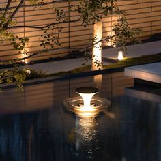 an illuminated fountain in the middle of a pool at night