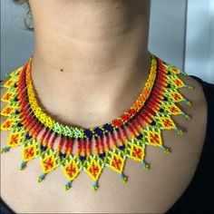 a woman wearing a multicolored beaded necklace on her neck with an earring