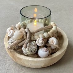 a candle sits in a bowl filled with seashells