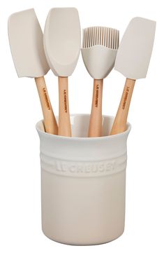 a white cup filled with wooden utensils