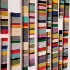 multicolored striped wall hangings on a white wall in an art gallery or office