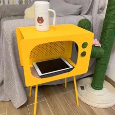 a yellow microwave oven sitting on top of a wooden table next to a cactus plant