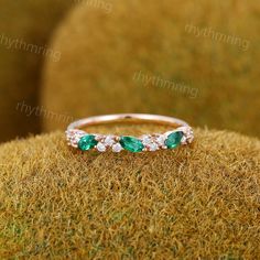 an emerald and diamond ring sitting on top of grass