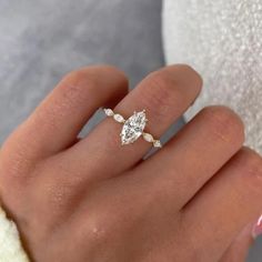 a woman's hand with a diamond ring on top of her finger and a white towel in the background