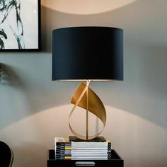 a black lamp sitting on top of a table next to a stack of books and a chair