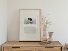 two vases are sitting on a dresser next to a framed photo and an art print