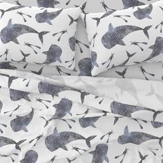 a bed covered in blue and white sheets with fish printed on the pillowcases