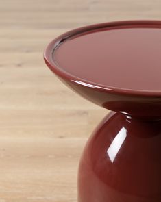 a red vase sitting on top of a wooden table