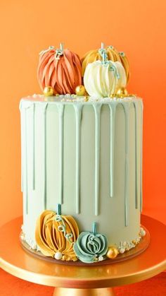 a cake with frosting and pumpkins on top is sitting on a gold plate