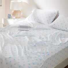 a bed with white sheets and blue stars on it