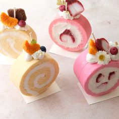 three different types of desserts are on display in the shape of spiral cakes with fruit and cream toppings