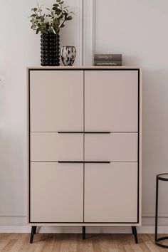 a white dresser with black handles next to a potted plant on top of it