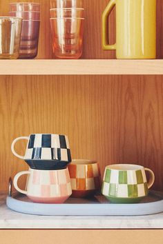 colorful cups and pitchers are sitting on shelves