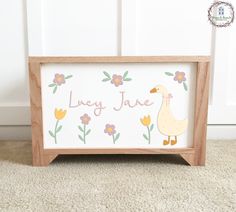 a wooden frame with an image of a duck and flowers painted on it that says lily jane