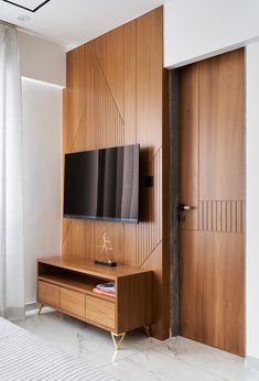 a flat screen tv mounted to the side of a wooden wall next to a bed