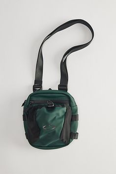 a small green bag with a black strap hanging from it's side on a white surface