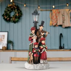 a group of figurines sitting on top of a table next to a christmas wreath