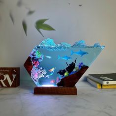 an illuminated glass bowl with sharks and other marine creatures in it on a marble surface