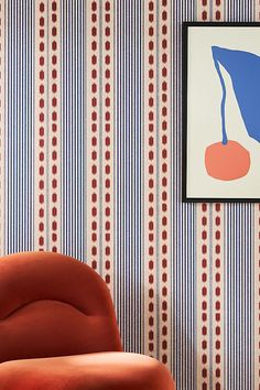 an orange chair sitting in front of a wall with a blue and red striped pattern