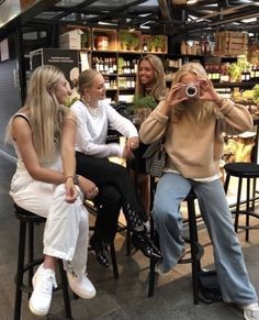 four women sitting at a table taking pictures