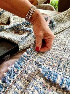 an old woman's hand on top of a knitted blanket with a sewing needle