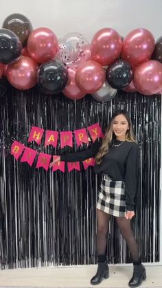 a woman standing in front of balloons and streamers with the words happy birthday written on it