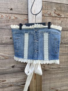 a blue jean skirt hanging on a wooden fence with a white ribbon tied to it