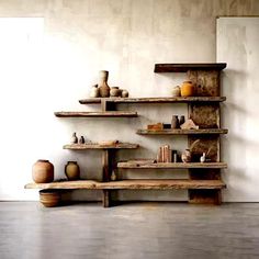 a wooden shelf filled with vases on top of it's sides next to a white wall