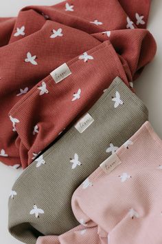 four folded cloths with small white birds on them, all in pink and grey