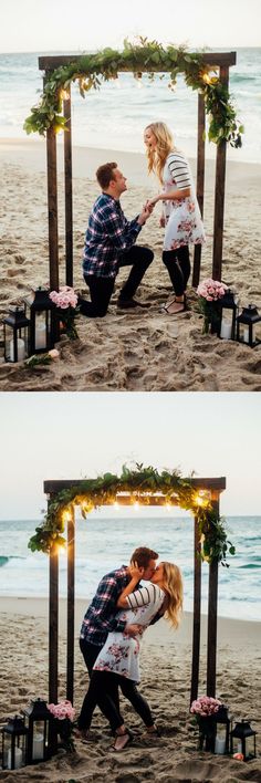 a couple kissing on the beach under an arch with lights and flowers around it, in front of the ocean