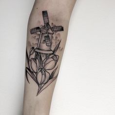 an anchor with flowers and a windmill tattoo on the arm, by artist mark taylor