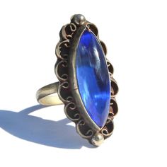 "Vintage Mexican blue glass Alpaca silver ring. Size 8. Long marquise / navette shaped cobalt blue glass cabochon stone bezel set in a decorative frame with filigree and granulation. Stamped \"Mexico\" on reverse side with a zig-zag etching (this was an old method assay offices used to scratch the piece to measure metal content). Such a stunning large statement ring with brilliant color. Acquired from the estate of a Mexican jewelry collector. 1.25\" length and 0.5\" width. Excellent condition." Mexican Blue, Decorative Frame, Mexican Jewelry, Turtle Charm, Vintage Mexican, Frame Decor, Brilliant Colors, Estate Jewelry, Statement Ring