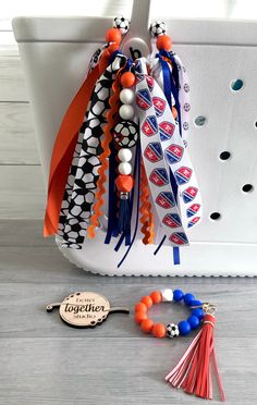 an orange, white and blue tasseled bag with some beads hanging from it