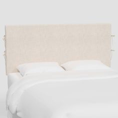 an upholstered headboard with white linens on the top and bottom sides