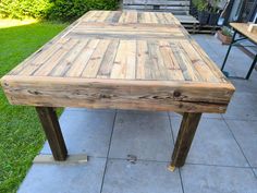 a wooden table sitting on top of a tiled floor next to a grass covered yard