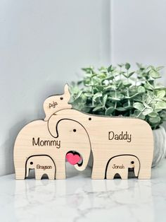 two wooden elephants standing next to each other on top of a white counter with a plant in the background