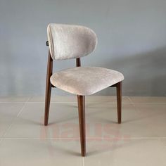 an upholstered chair with a wooden frame and fabric seat padding, in front of a gray wall