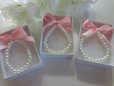 three small boxes with pearls and pink bows on the top one has a necklace in it