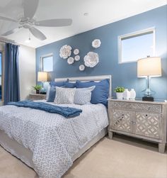 a bedroom with blue walls and white bedding in front of a large window that overlooks the ocean