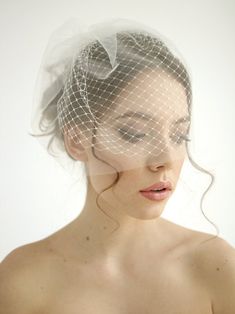 a woman with a veil on her head wearing a white dress and wedding hair comb